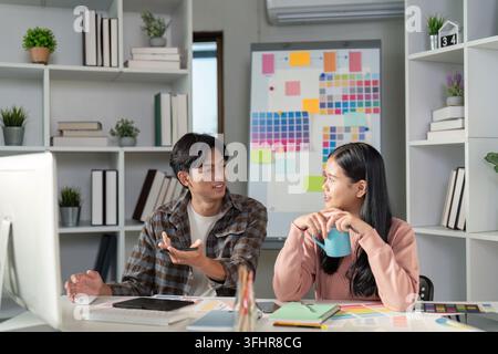A design team collaborates on graphics projects in a vibrant office exchanging ideas and creativity. Stock Photo
