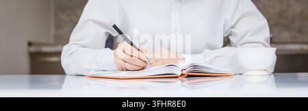 Focused young woman entrepreneur deep in thought, working at table writes notes Stock Photo