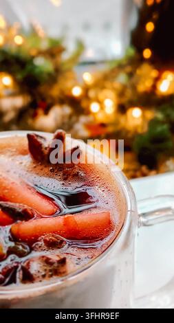 Christmas mulled wine on blurred background of bright lights. Traditional New Year's hot drink made from red wine, orange, cinnamon, apples and star a Stock Photo