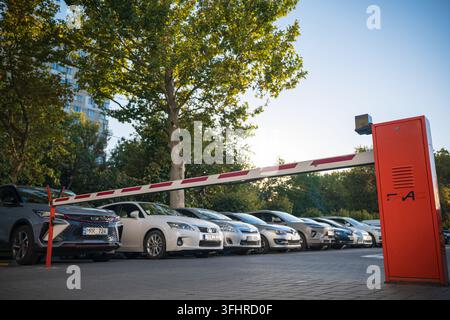 CHISINAU, MOLDOVA - SEPTEMBER 8, 2026: Automatic red parking barrier gate arm closed at the entrance of a crowded urban outdoor parking lot. Stock Photo