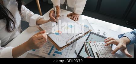 A focused team analyzing financial reports and budget data, using charts and calculations, to ensure accurate decision-making in a modern office setti Stock Photo