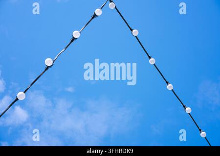 White energy-saving light bulbs on a wire, blue sky, a beautiful decoration for the evening city Stock Photo