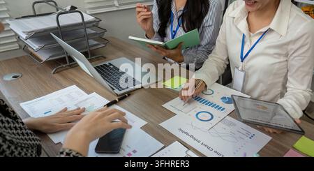 Diverse team analyzing data charts and discussing strategies during a focused business meeting in a modern office Stock Photo