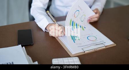 Financial expert preparing detailed reports and analyzing data trends in a modern workspace. Stock Photo