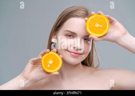 A woman is holding two oranges in her hands and smiling Stock Photo