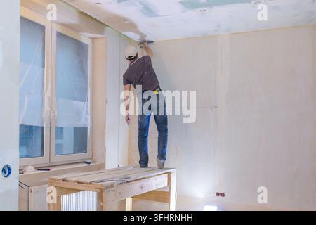 Worker make repairs in new apartment. Man plaster walls and ceilings Stock Photo