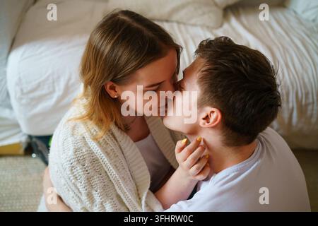 Happy positive young couple hugging and relaxing sitting by couch, cheerful Stock Photo