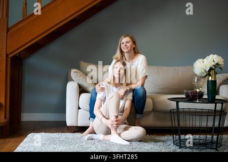 Portrait smiling family, middle aged mother and adult daughter hugging while Stock Photo