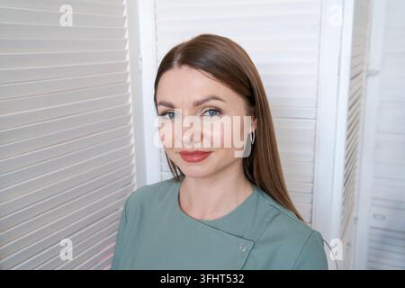 Portrait professional beautician smiling young woman in green uniform Stock Photo