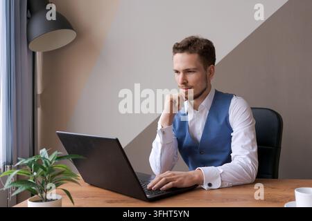 Businessman thinking about online project, looking at laptop at workplace Stock Photo