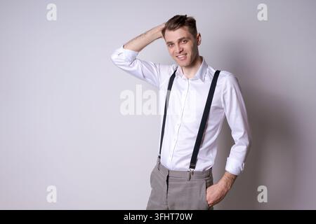 A man in a white shirt and suspenders is smiling Stock Photo