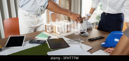 Engineers working at their workstation, skillfully finalizing innovative project designs using high-tech tools and models focused on sustainability. Stock Photo