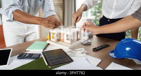 A diverse team of engineers discussing architectural designs and sustainability features during a brainstorming session in a modern office. Stock Photo