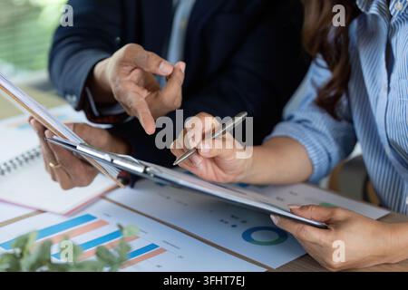 Close-up of professionals engaged in a detailed financial discussion, analyzing charts and documents for insights. Stock Photo