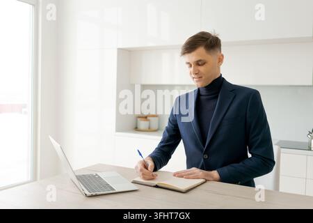 Man in a suit is writing in a notebook Stock Photo