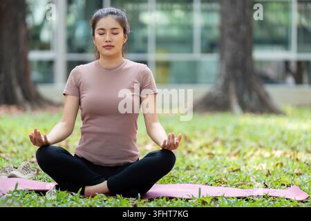 Wellness through Meditation. Young woman practicing mindfulness outdoors in a serene park. Stock Photo