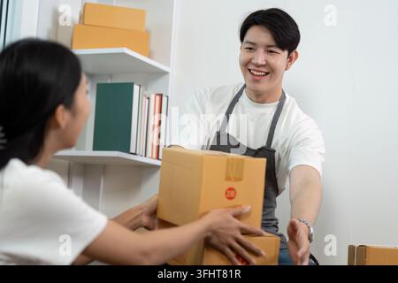 Couple collaborating in a modern workspace, sharing packages and ideas. Stock Photo