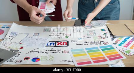 A creative team collaborates on design concepts, sharing ideas and feedback while reviewing project materials on a table. Stock Photo