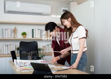 A vibrant workspace where two young professionals share ideas and feedback on user experience design concepts. Stock Photo
