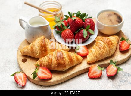 Delicious french breakfast with croissants, coffee, strawberries, milk and honey Stock Photo