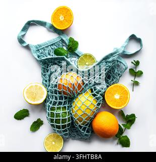Ripe whole citrus fruits in string bag on white background Stock Photo