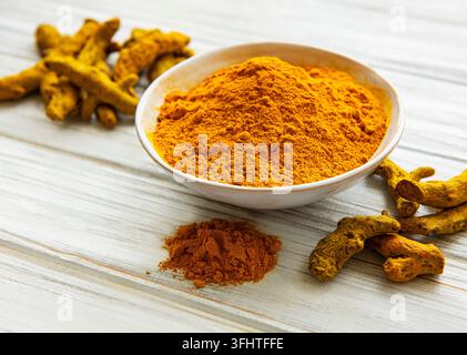 Bowl with turmeric powder and roots  on a wooden background Stock Photo