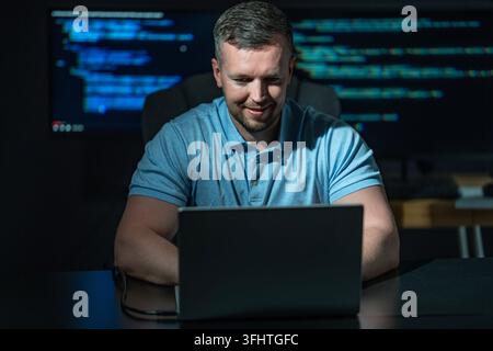 Hacker uses computer for cyber attack. Hacker writes malicious code on screen. Hacker monitors secure network activity. Hacker creates digital Stock Photo
