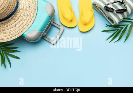 Suitcase, beach towel, flip flops, sunglasses and a straw hat suggesting summer vacation travel Stock Photo
