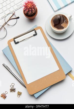 Home office desk workspace with blank clipboard, keyboard, coffee, cactus, glasses, pen, notebook, and binder clips, inviting creativity and productiv Stock Photo