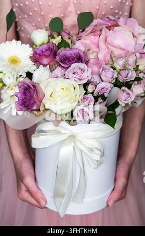 Flowers set. Beautiful luxury bouquet of  flowers in a white round box in female hands. Stock Photo