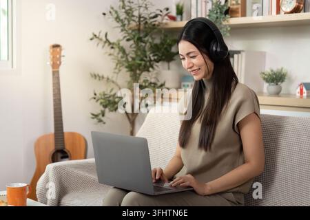 Remote Work and Focused Learning. Young woman using laptop with headphones. Stock Photo