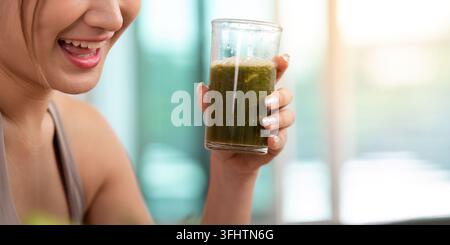 Enjoying Nutrition. Woman savoring a green smoothie in a glass. Stock Photo