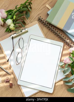The workspace is organized with a tablet, glasses, stationery, and green foliage, all arranged harmoniously to create a tranquil atmosphere for focus Stock Photo