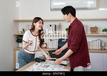 Two young professionals engage in a collaborative UX and UI design session, sharing ideas and sketches in a modern workspace. Stock Photo