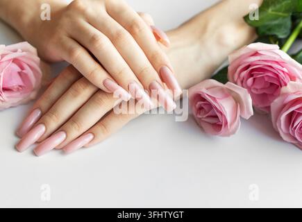 Woman showing her beautiful pastel pink manicure near pink roses Stock Photo