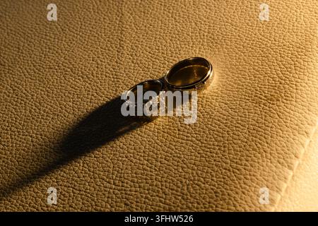 Elegant Diamond Wedding Rings on Textured Leather Surface with Warm Lighting Stock Photo