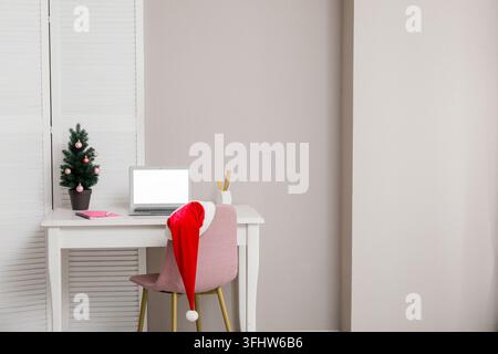 Remote work during holidays, home office setup with laptop and santa hat for seasonal business planning and festive freelance productivity in December Stock Photo