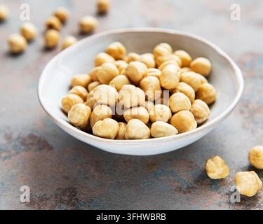Peeled hazelnuts in a bowl on grey concrete background Stock Photo