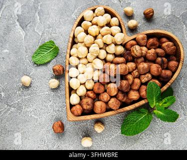 Peeled hazelnuts in a bowl on grey concrete background Stock Photo