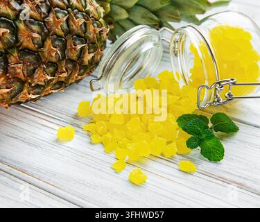Sweet pineapple succade cubes on white wooden background Stock Photo