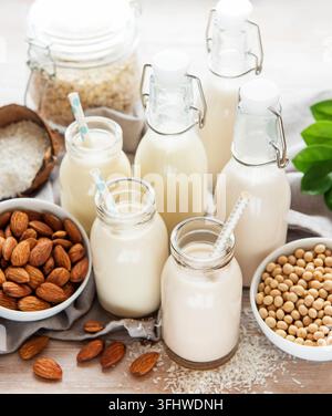 Alternative types of vegan milks in glass bottles on a  concrete background. Top view Stock Photo