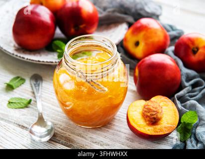 Nectarine jam with fresh nectarines on a white wooden table Stock Photo