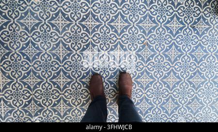 Feet on decorative tile floor in a building with patterned design Stock Photo