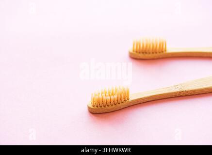 Bamboo toothbrushes on light pink background Stock Photo