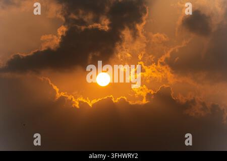 Golden rim of sunlight breaking through clouds at sunset Stock Photo