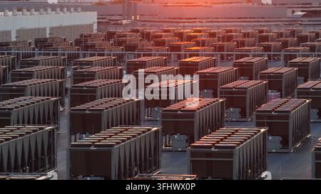 Aerial sunset view of data center in Ashburn, Virginia with rows of industrial cooling units and rooftop HVAC systems glowing in warm light across lar Stock Photo