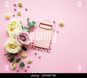 Clipboard and flowers on pink background Stock Photo