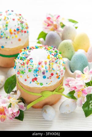 Delicious easter cakes decorated with colorful sprinkles and eggs on white table Stock Photo