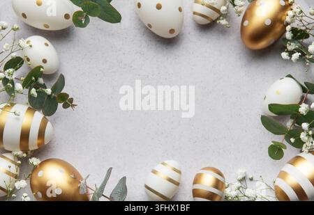 Easter eggs with gold and white decorations forming a frame on a gray background Stock Photo