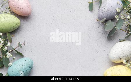 Easter eggs and eucalyptus leaves forming a frame on gray background Stock Photo